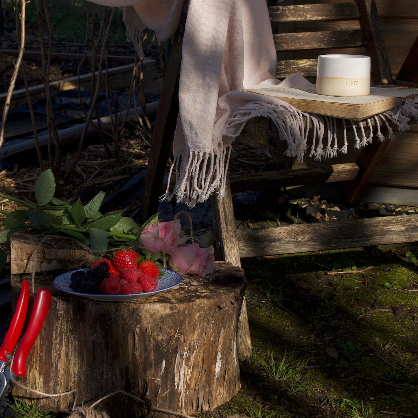 Outdoor setting with a wooden stool, plaid blanket, and rustic decor.